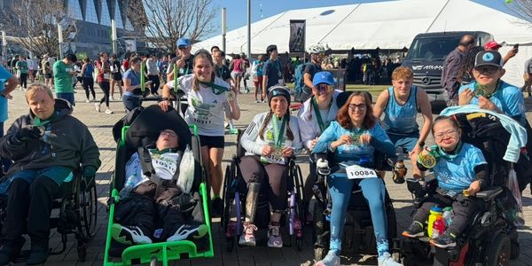 Group of athletes with disabilities proudly showing their medals outdoors after a race.