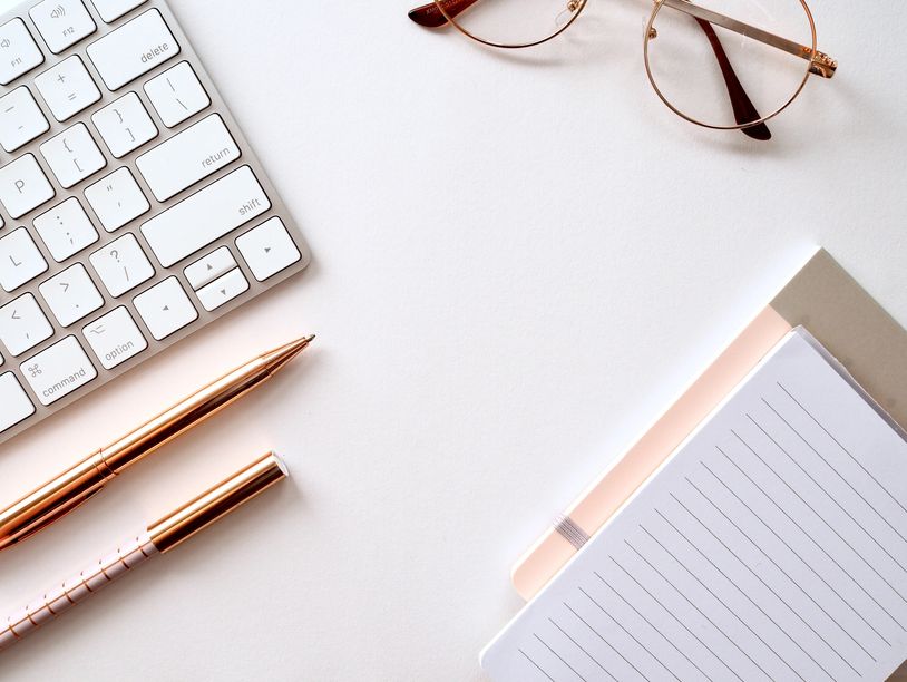 A keyboard, pens, notebooks and glasses