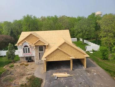 House under construction with wooden framing and a large garage.
