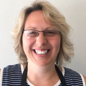 Two smiling female stylists, Sue and Betsy, wearing glasses and casual outfits.