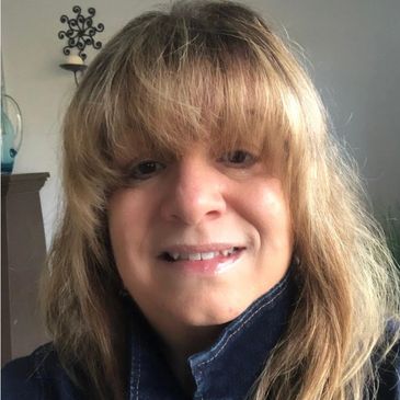 Portrait of Betsy, a stylist, smiling in a denim jacket.