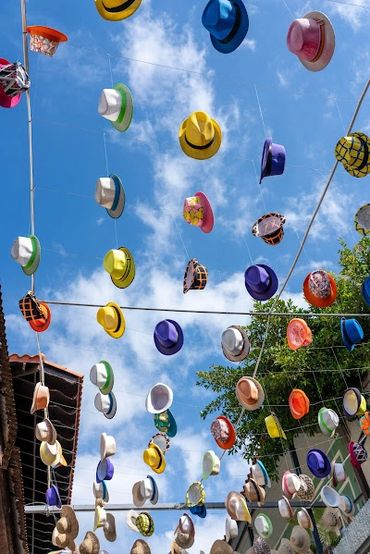 Colorful hats hanging on strings against a blue sky.