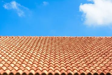 Red clay tile roof under a blue sky with clouds.