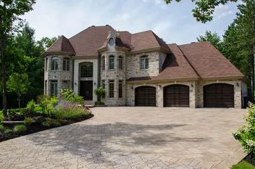 Elegant stone mansion with a large driveway and three-car garage.
