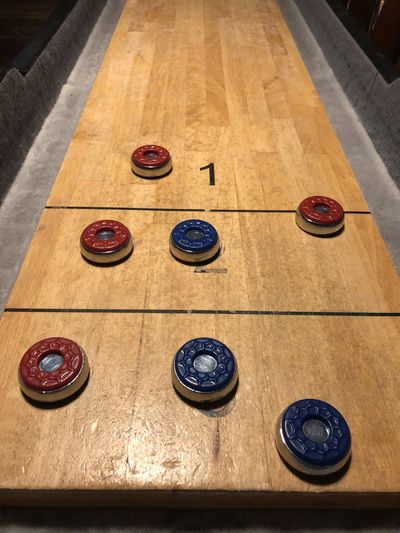 A top-down view of a shuffleboard table with red and blue pucks.