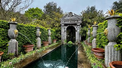A formal garden with a pound and fountains.