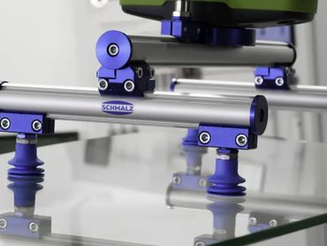 Close-up of a Schmalz vacuum gripping system lifting a glass sheet.
