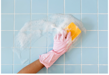 Cleaning a bathroom tile wall with a sponge