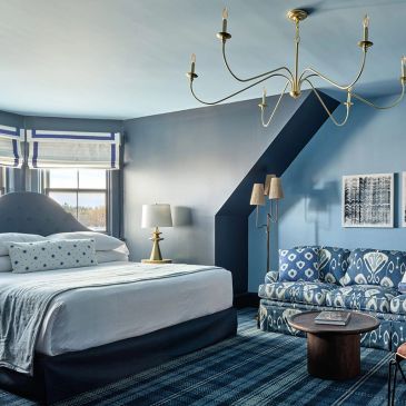 Stylish blue bedroom with patterned sofa and modern chandelier.