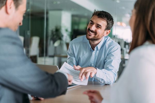Smiling man passing a contract across a table.