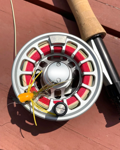 Close-up of a fishing reel with red line and a yellow fly lure.