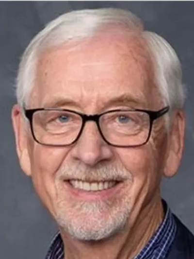 Smiling elderly man with glasses and white hair.
