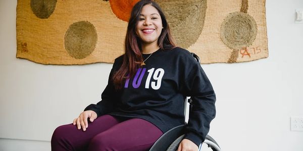 Johileny in her wheelchair. Straight hair a NYU19 black sweatshirt).