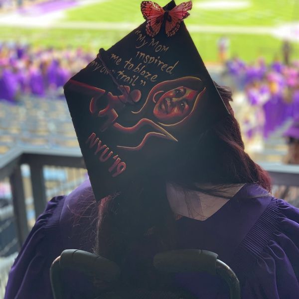 Picture of graduation cap. Design of active wheechair sign and a painting of a women's faca (Mom).
