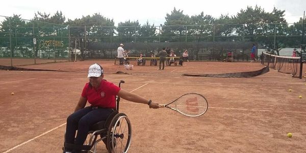 Johileny on a tennis court doing a back hand with the racket.