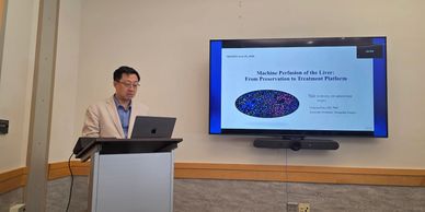 Speaker presenting on liver machine perfusion at a conference.