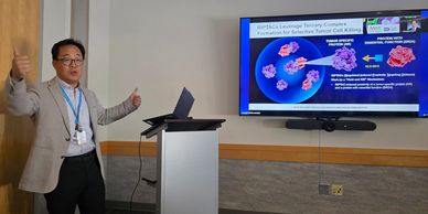 A man presenting scientific research with a visual slide on cell killing mechanisms.