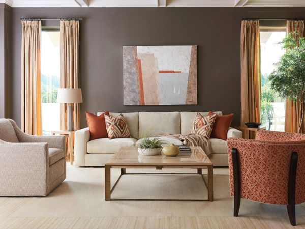 Elegant living room with beige and rust tones, featuring a modern sofa and patterned chairs.