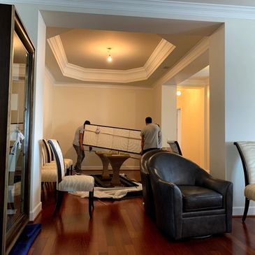 Two men moving a large piece of furniture in a spacious, well-lit room.