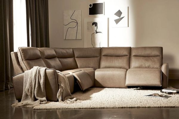 Modern brown leather sectional sofa with a cozy throw in a minimalist living room.