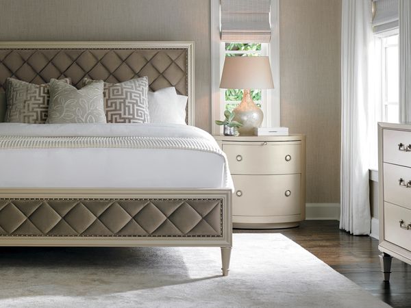 Elegant bedroom with a tufted bed, patterned pillows, and a stylish nightstand with a lamp.