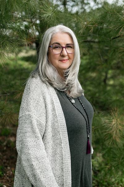 Amanda Wilson, Registered Psychotherapist in a gray sweater with trees in the background