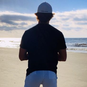 Man facing sunrise on a beach with Gobuca Hip and Leg band around his legs