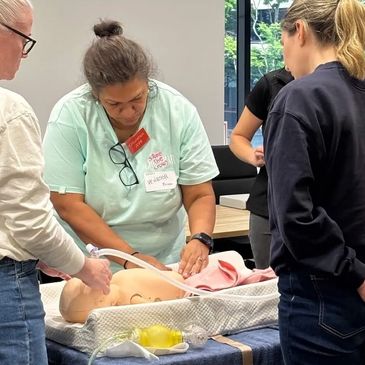 People practicing infant CPR on a manikin.
