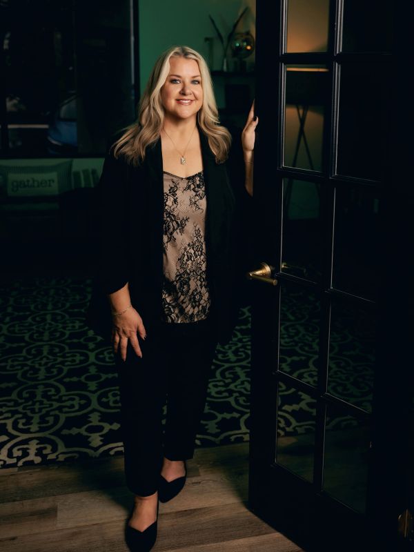 Smiling woman standing by a door indoors.