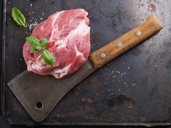A picture of a cut of meat on top of a classic butchers meat chopper.