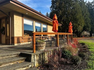 Outdoor patio seating with orange umbrellas at a small cafe on a sunny day.