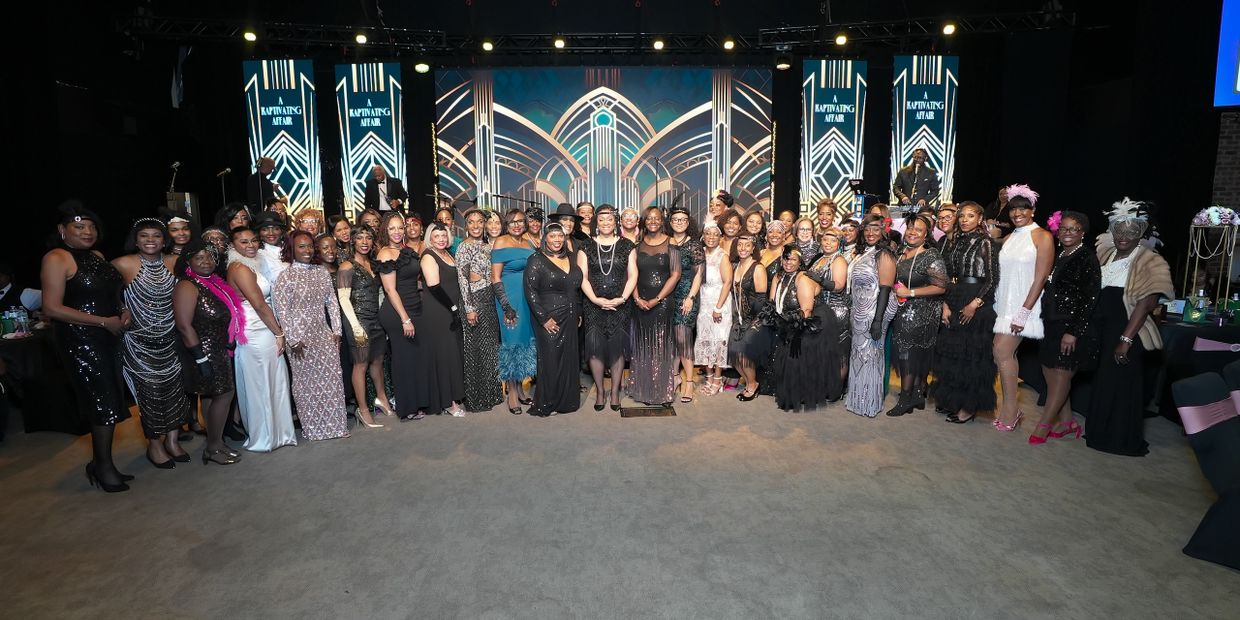 Large group of women dressed in 1920s flapper-style attire posing at an event.