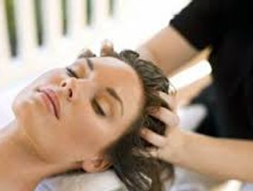 Picture shows a lady getting the Moroccan Oil Scalp Treatment while relaxing on a massage table.