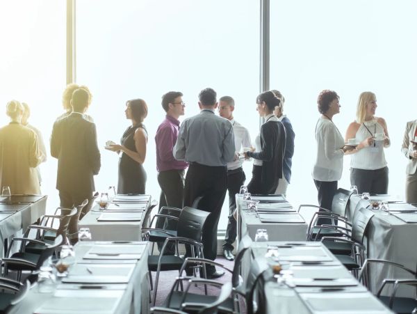 People socializing in a conference room during a break.