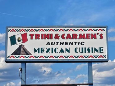 PICTURE OF A LARGE ROAD SIGN FOR TRINI & CARMENS RESTAURANT