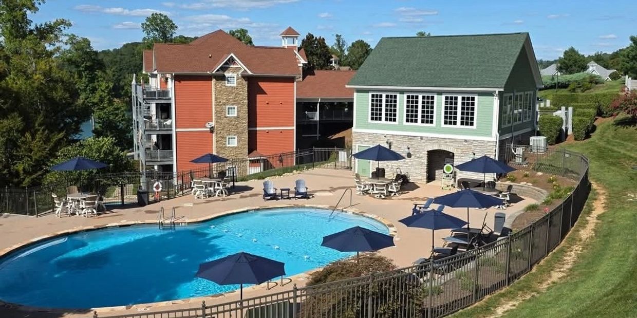 A residential pool area with umbrellas and lounge chairs on a sunny day.