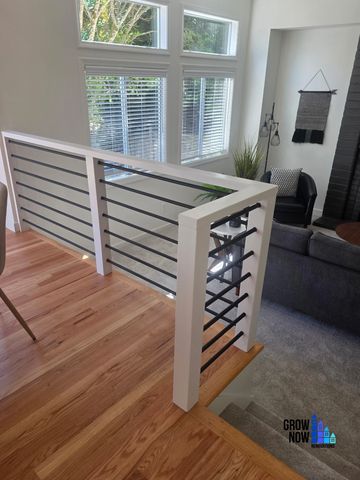 Modern stair railing with black horizontal bars and white frame.