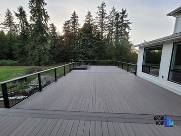 Spacious deck attached to a modern house with forest backdrop.
