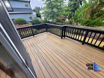 Empty wooden deck with black railing.