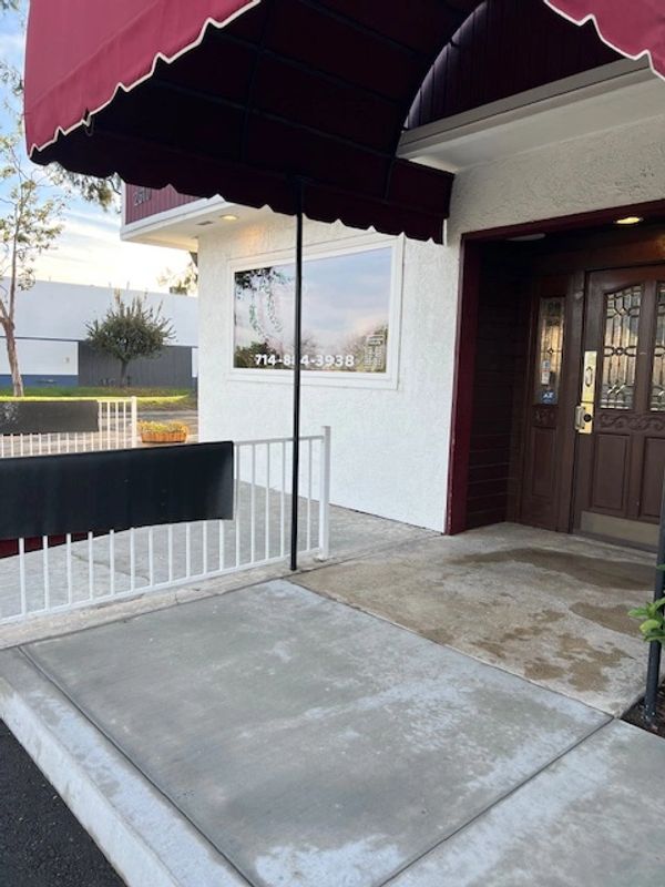 Entrance of a building with a maroon awning and glass-paneled door.