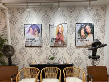 Cozy salon waiting area with wicker chairs and hair care posters.