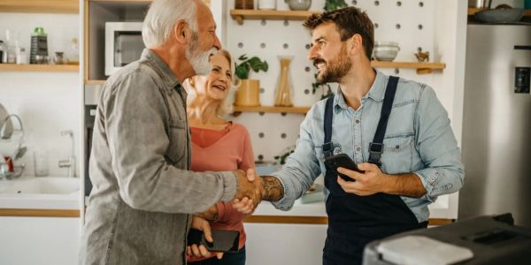 Man shaking hands with an older man while a woman smiles.