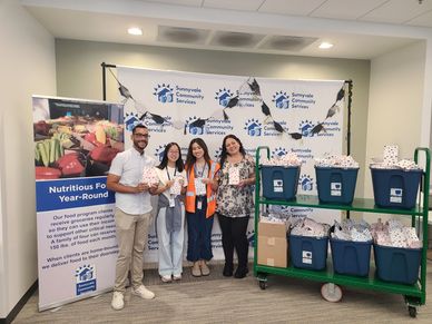 Four people holding food packages at Sunnyvale Community Services.