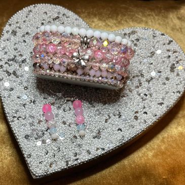Pink and white beaded bracelets and earrings on a heart-shaped bead tray.
