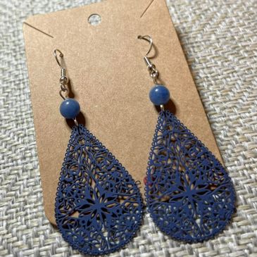 Blue floral filigree teardrop earrings with round blue beads on a brown card.