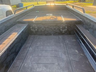 Cargo area of a utility boat with speakers and storage compartments.