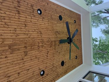 Outdoor ceiling with wooden planks, lights, and a ceiling fan.