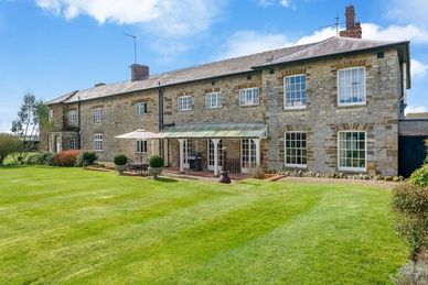 Historic british home , green lawn blue sky with a few white clouds