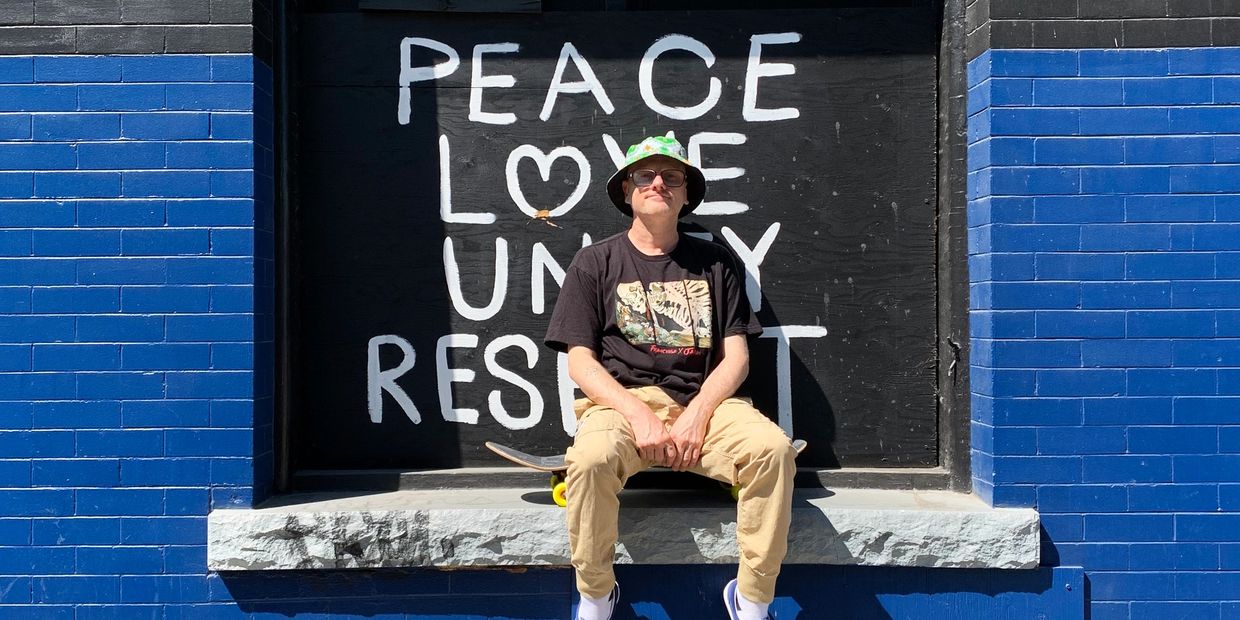 Rennie Foster on skateboard in front of PLUR graffiti.