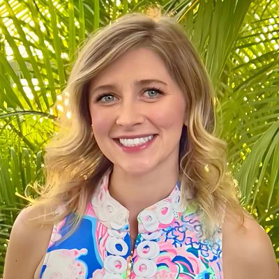 Smiling woman with wavy blonde hair in colorful dress.